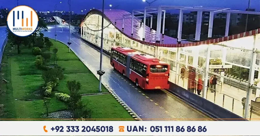 A red Metro bus parked at a well-lit Islamabad Metro station at night, with lush green surroundings, showcasing the city’s expanding public transport system through new feeder routes approved by CDA.